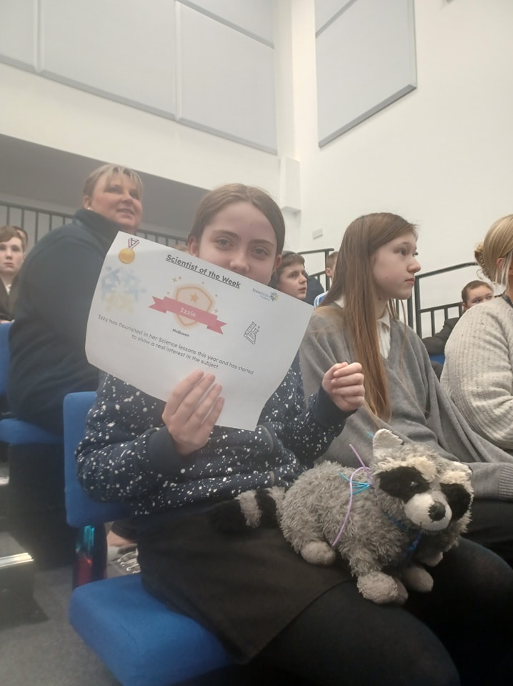 A girl is seen smiling for the camera and showing a certificate she has won for participating in an activity.