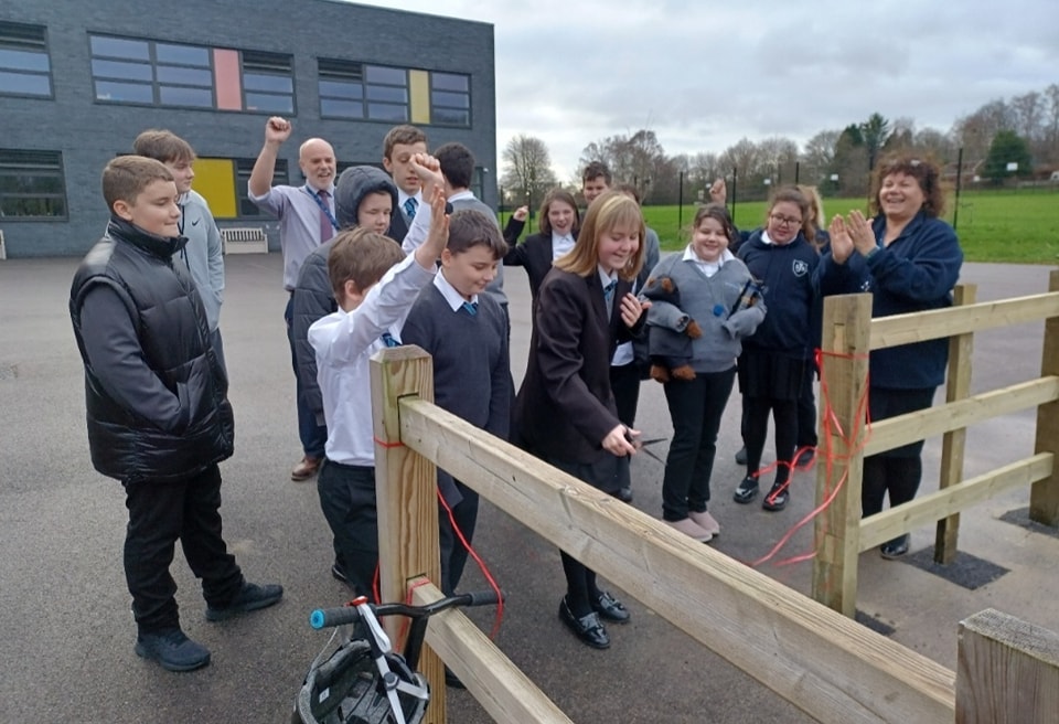 A group of students are pictured with two members of staff, as they cut the ribbon to open a new outdoor Gym on the academy grounds.