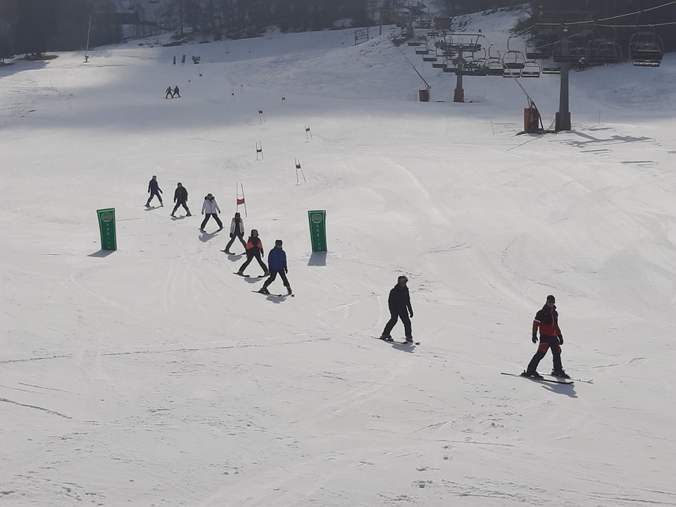 Several Leigh Academy Snowfields students are seen descending down a snowy slope on Skis from a distance during a school trip abroad.