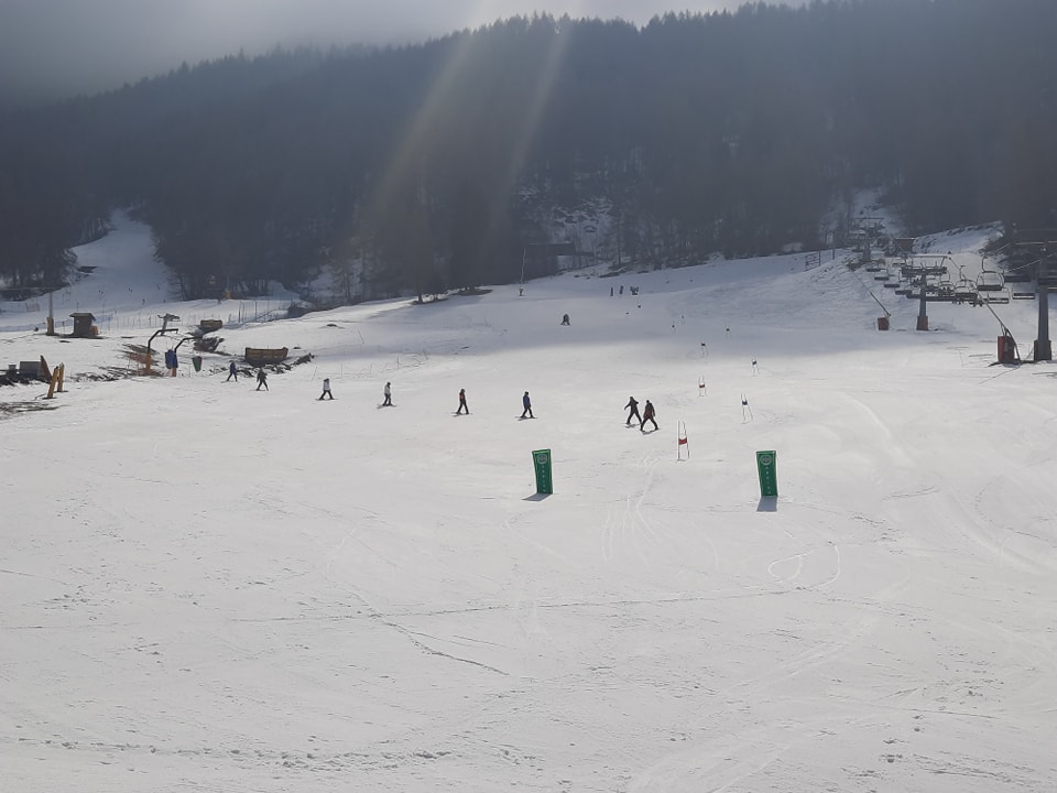A snowy landscape with trees pictured in the background and a group of Leigh Academy Snowfields students seen skiing together.